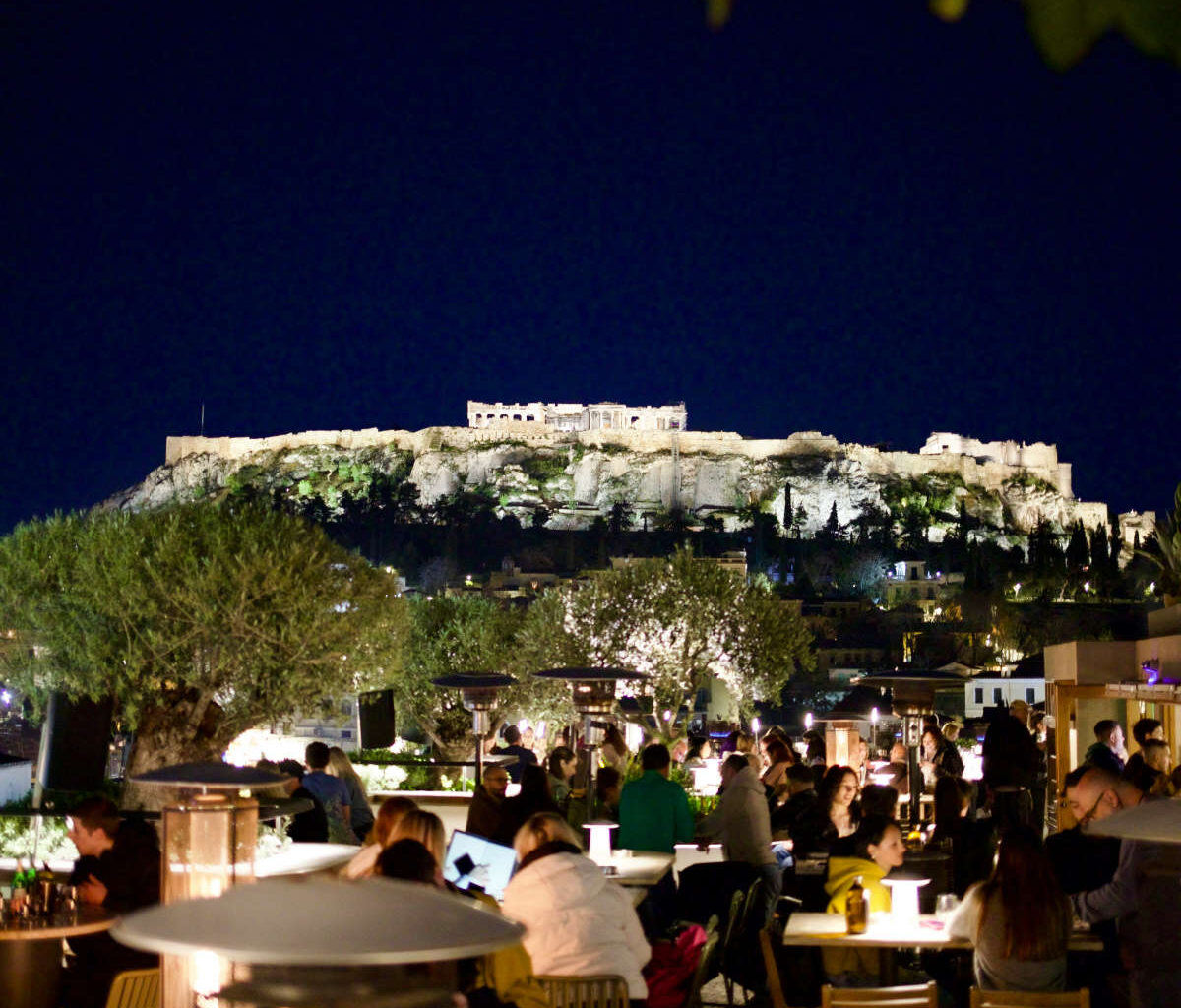 A vibrant rooftop bar in Athens overlooking the illuminated Acropolis, the perfect start to a Greece itinerary 10 days in 2026.