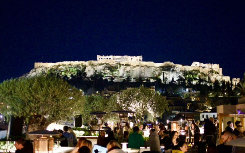 A vibrant rooftop bar in Athens overlooking the illuminated Acropolis, the perfect start to a Greece itinerary 10 days in 2026.