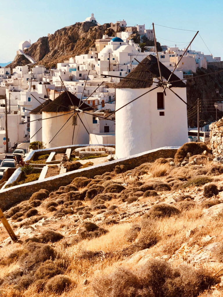 Traditional white windmills in front of the historic climbing Chora town, showcasing the best Greek islands for couples in 2026.
